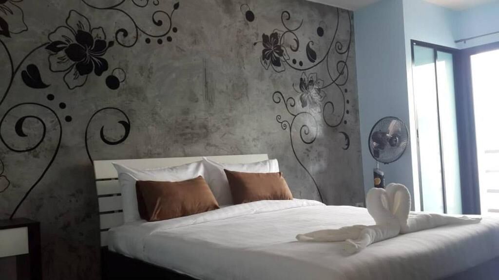Un lit bien fait, avec des oreillers blancs et bruns, une couverture blanche et une serviette blanche pliée posée sur le lit.