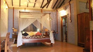 A traditional four-poster bed with a canopy, wooden furniture, and a brick wall. - Lake Serenity Boutique Hotel (Kuruwita)