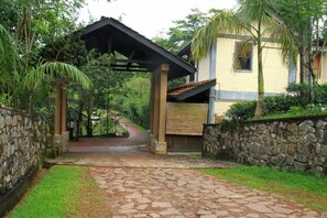 A pathway leading to a house with a stone wall on one side and a covered area on the other.