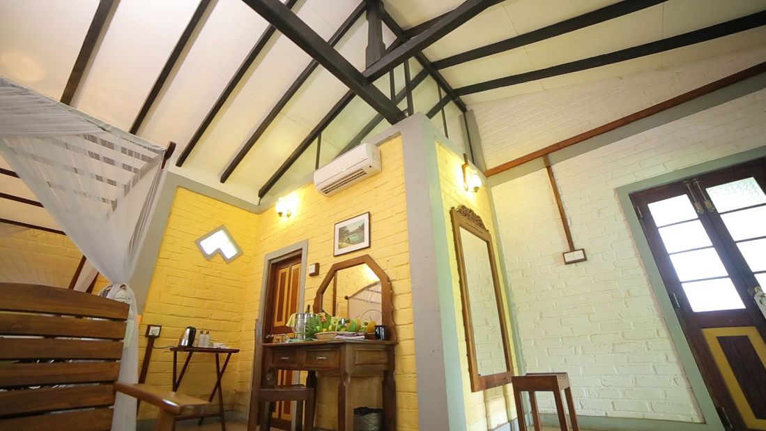 A room with a high ceiling, exposed beams, a wooden desk, a mirror, and a window with a view.