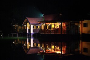 A waterfront hotel with a reflection in the water, featuring a dining area and a bar. - Lake Serenity Boutique Hotel (Kuruwita)