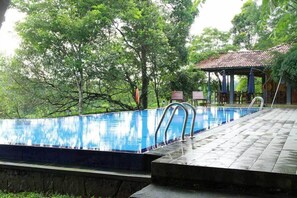 A swimming pool with a tiled deck and a gazebo in the background. - Lake Serenity Boutique Hotel (Kuruwita)