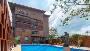 A modern building with a pool, outdoor seating, and a statue. - FarmHouse Hotel Ranong (Ranong)