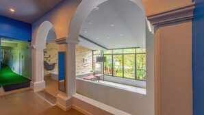 A spacious indoor area with high ceilings, arched doorways, and a large window offering a view of greenery outside. - FarmHouse Hotel Ranong (Ranong)