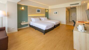 A hotel room with two beds, a desk, a chair, and a lamp.