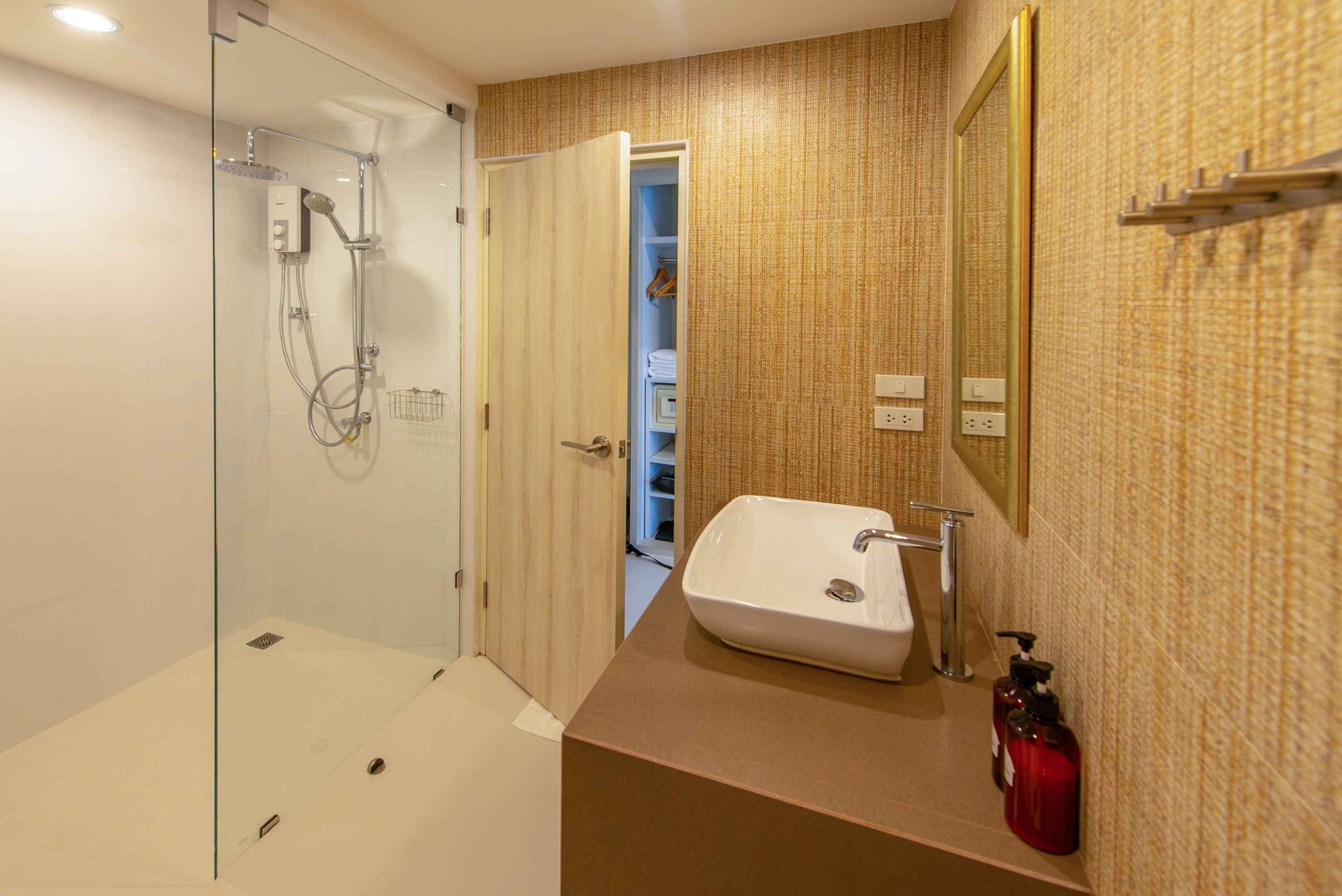 Un baño moderno con ducha de vidrio, lavamanos blanco y espejo.