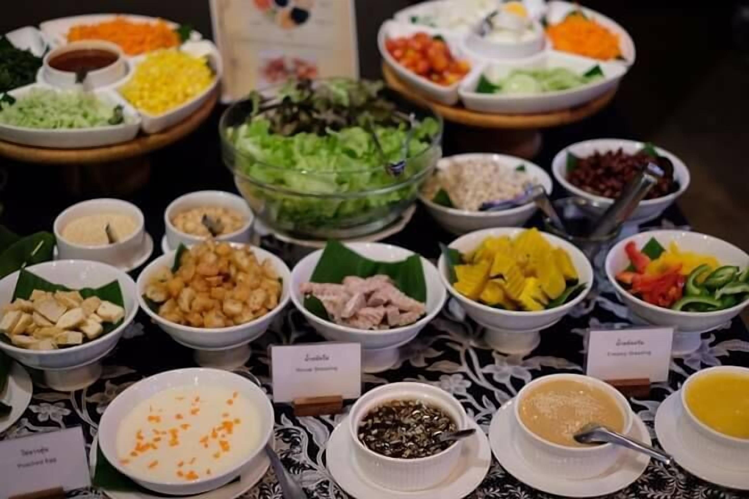 Ein Buffet mit verschiedenen Speisen, darunter Salate, Früchte und unterschiedliche Dips.