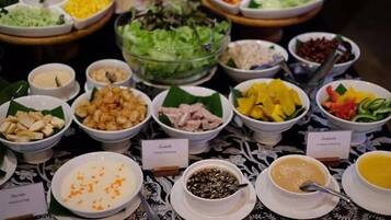 Ein Buffet mit verschiedenen Speisen, darunter Salate, Früchte und unterschiedliche Dips.