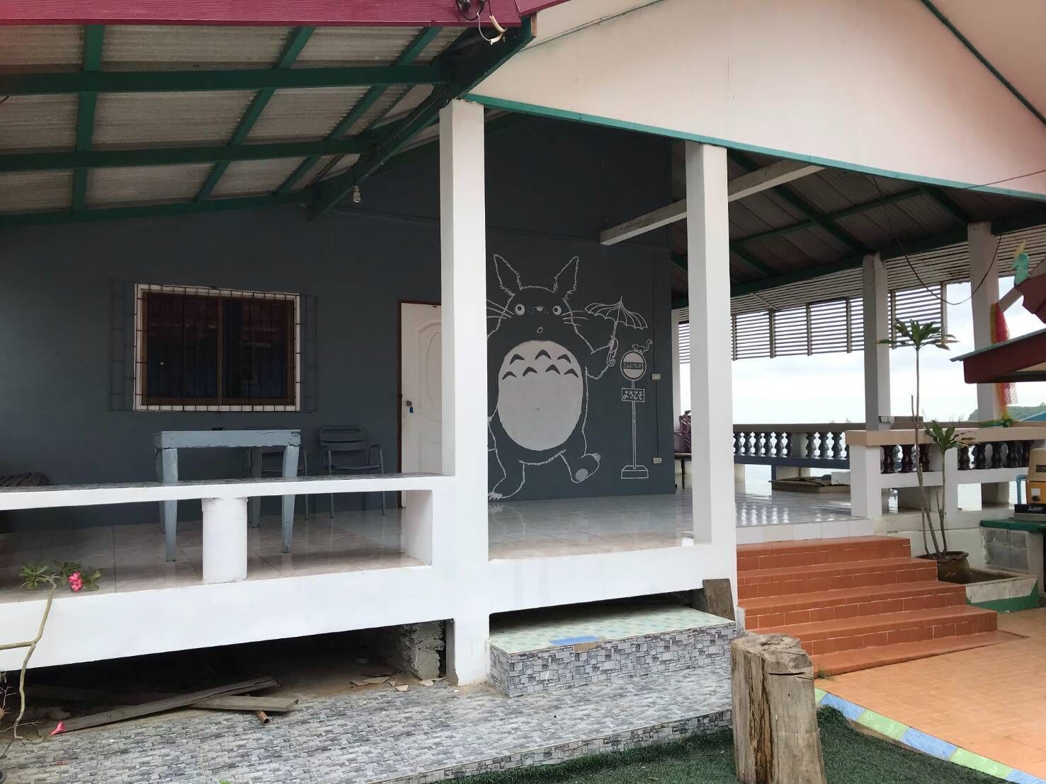 A covered outdoor area with a white railing, a door, and a mural of a cartoon character.