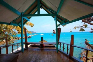 Une terrasse en bois offrant une vue sur la mer et les bateaux.