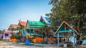A row of colorful houses with distinct roofs, a small dock, and a clear view of the sea. - Rimtalay Resort Koh Si Chang (Ko Sichang)