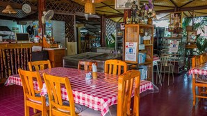 A restaurant with wooden tables and chairs, a red and white checkered tablecloth, and a variety of decorations and items on shelves. - Rimtalay Resort Koh Si Chang (Ko Sichang)