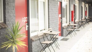 A row of outdoor tables and chairs along a building's exterior wall. - Siesta Central Apartments (Sale)