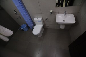 Un baño con inodoro, lavamanos y un cubo azul.