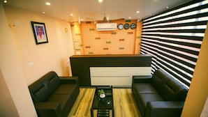A modern living room with a sofa set, a coffee table, and a brick-patterned wall with a ceiling fan.