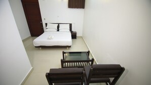 A small, neatly arranged bedroom with a bed, bedside table, and two chairs.