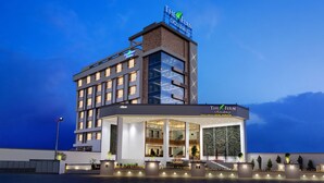 Ett modernt hotell med en framträdande skylt som lyder ”The Fern Residency”. Byggnaden har flera våningar och en blandning av glas- och tegelbeklädda fasader, stora fönster och en väl upplyst entré.