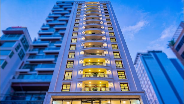 Un hotel de gran altura con una entrada destacada, varios balcones y una fachada bien iluminada.