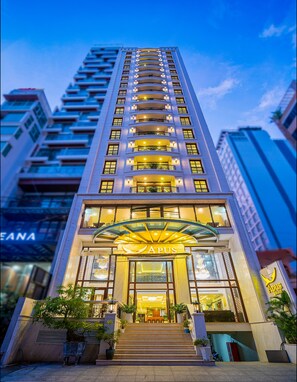 A high-rise hotel with a prominent entrance, multiple balconies, and a well-lit facade. - Apus Hotel (Nha Trang)