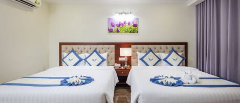 Une chambre d’hôtel avec deux lits, une table de chevet, une lampe et un climatiseur fixé au mur.