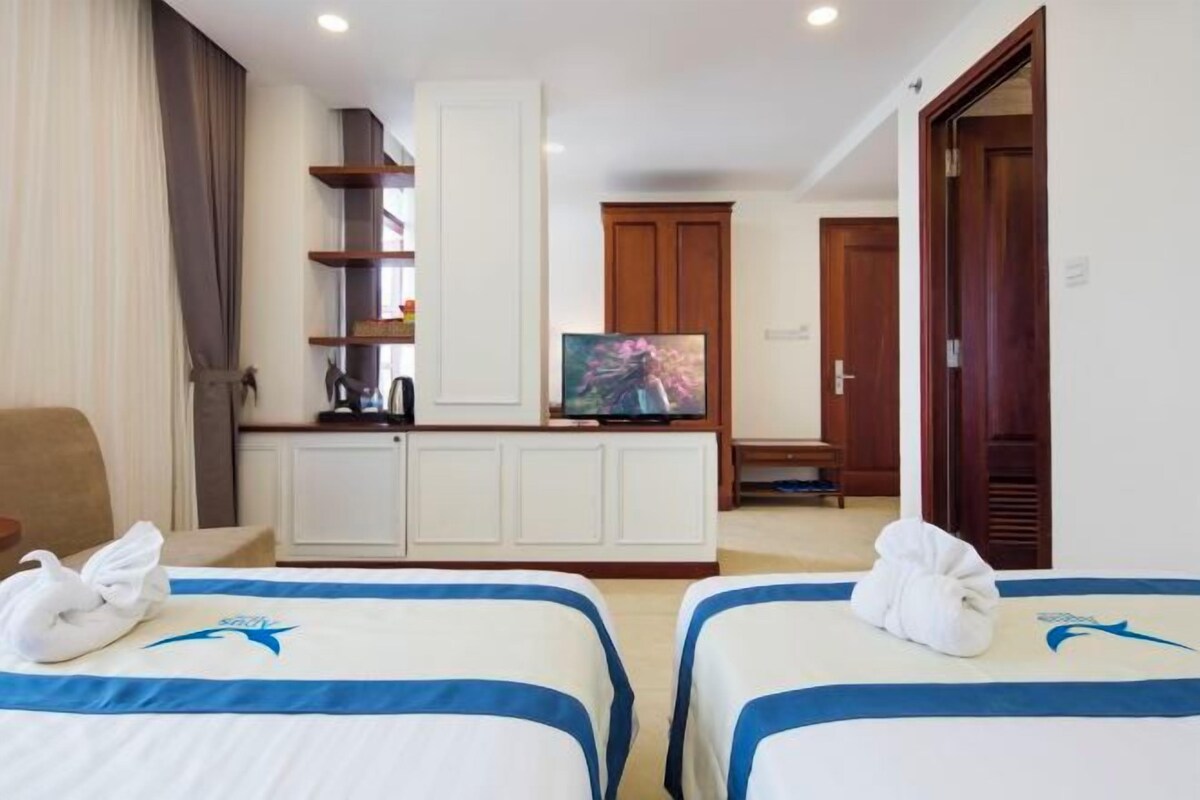 Habitación de hotel con dos camas, un televisor, un armario y una puerta.