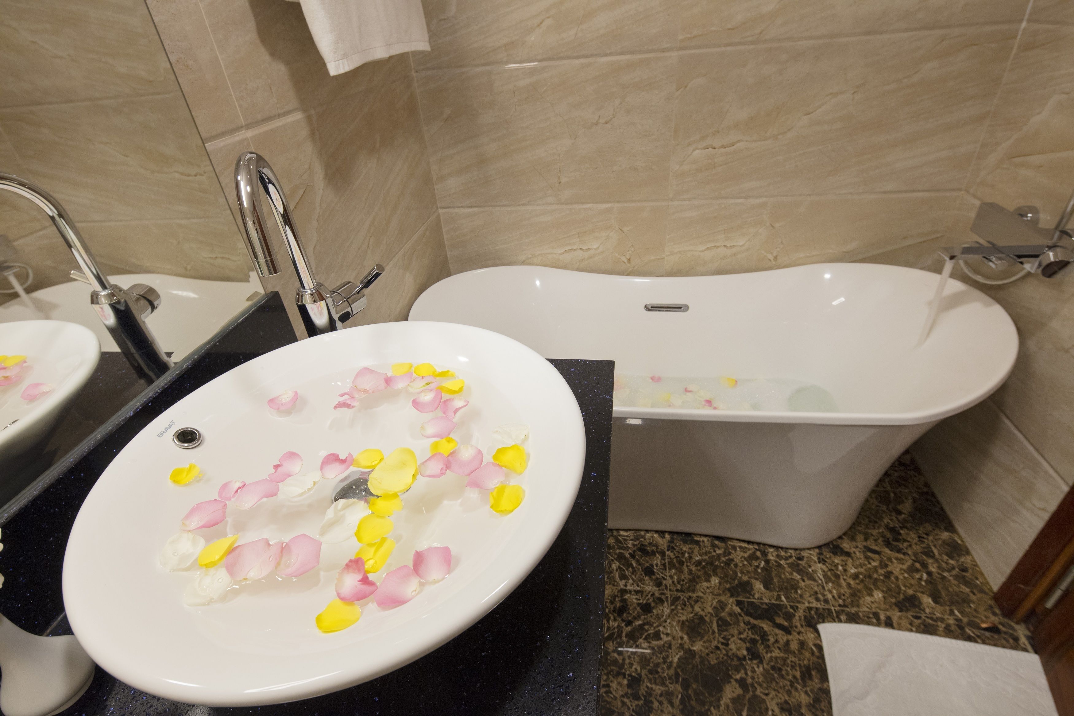 A bathroom with a sink and bathtub, both with water running.