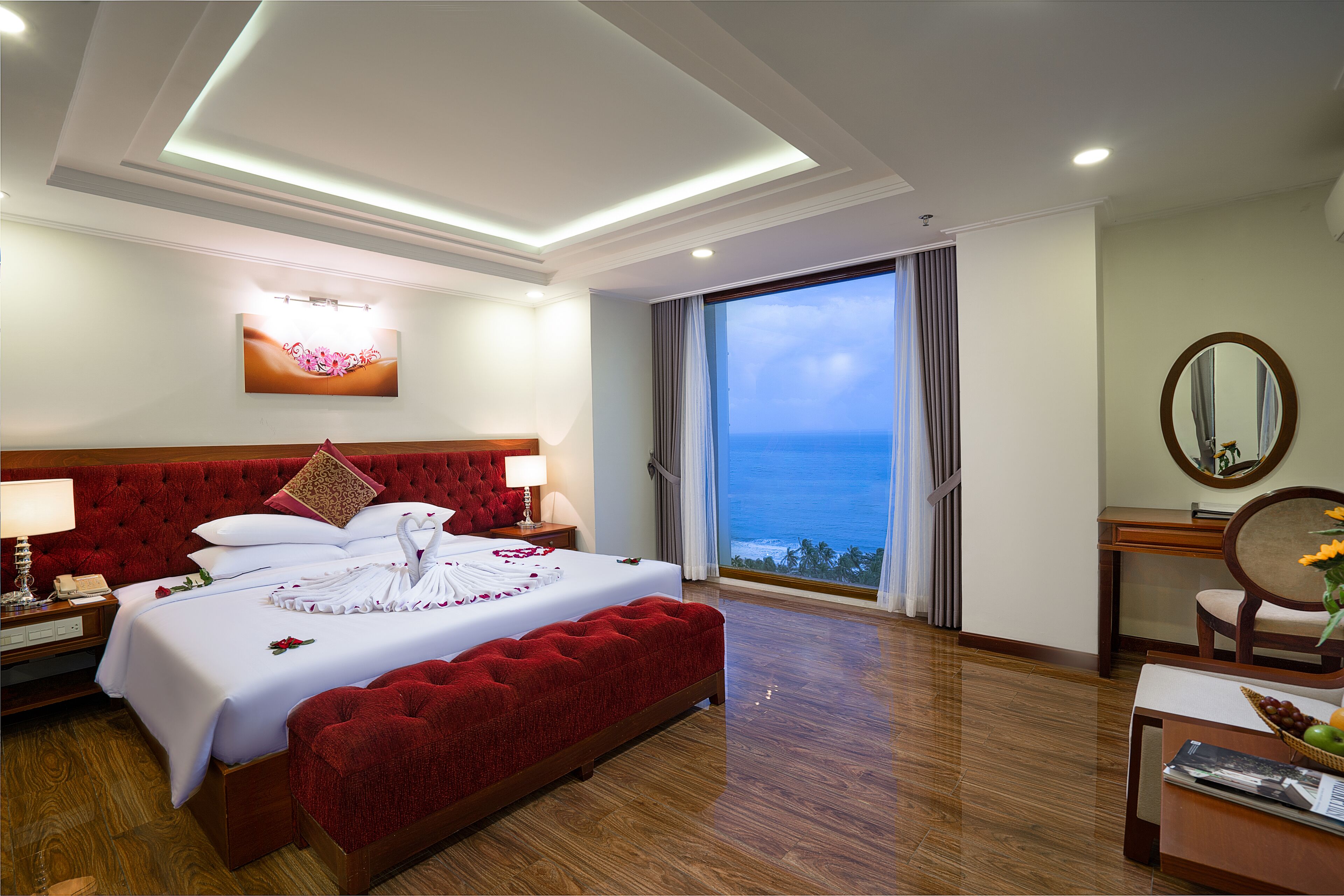Camera d'albergo con un letto grande, una scrivania, una sedia e vista sull'oceano.
