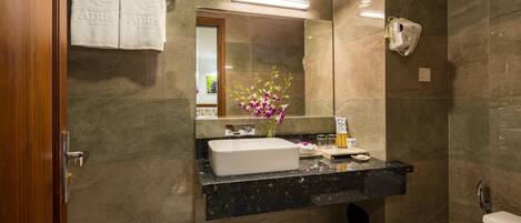 Un baño moderno con lavamanos de mármol, un espejo y un inodoro.