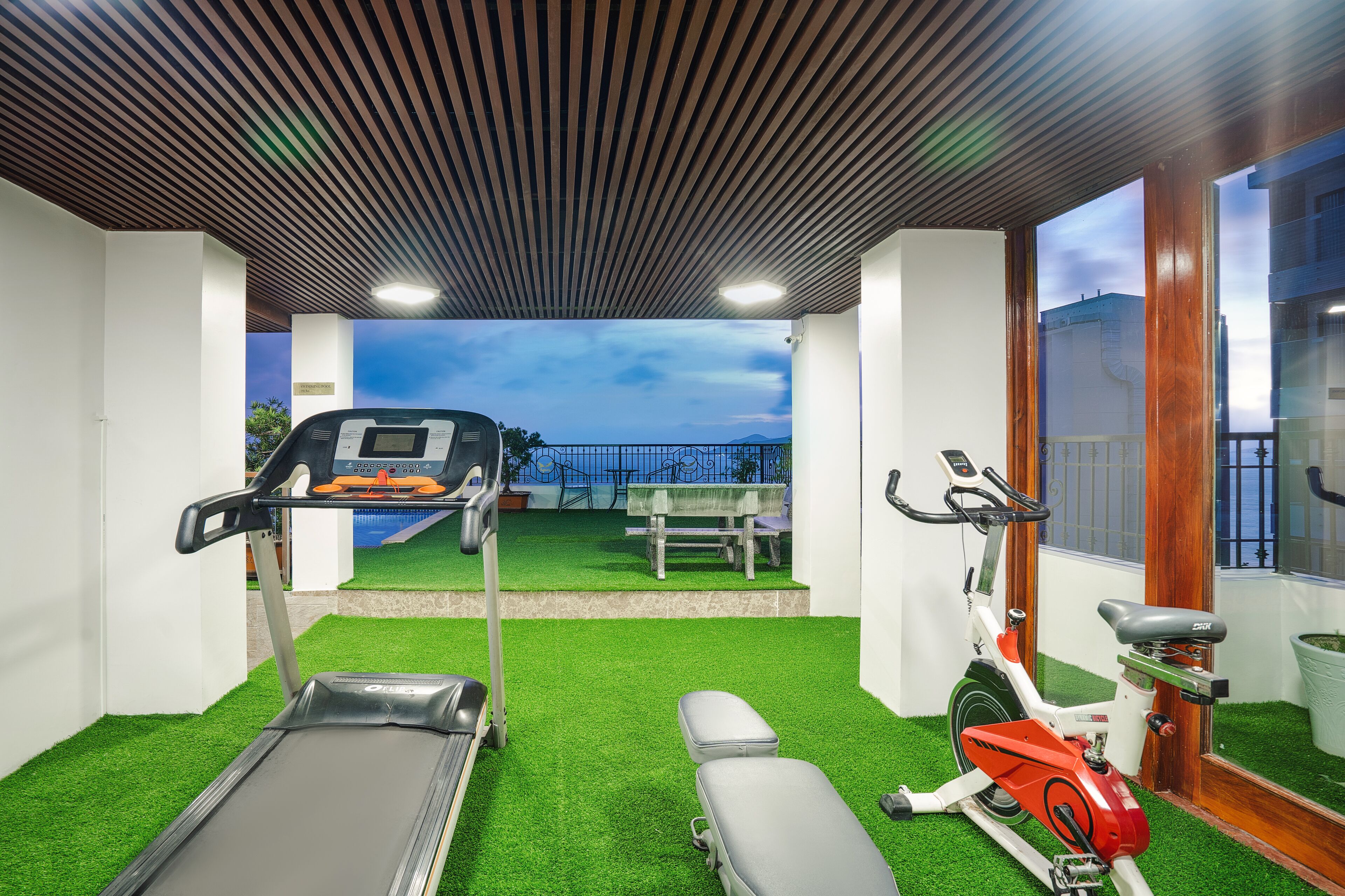 Een sportschool met een loopband, een hometrainer en een trainingsbank.