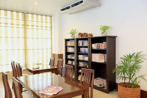 Enjoy meals at the large dining table surrounded by comfortable chairs, with a bookshelf filled with books and decorative items nearby.