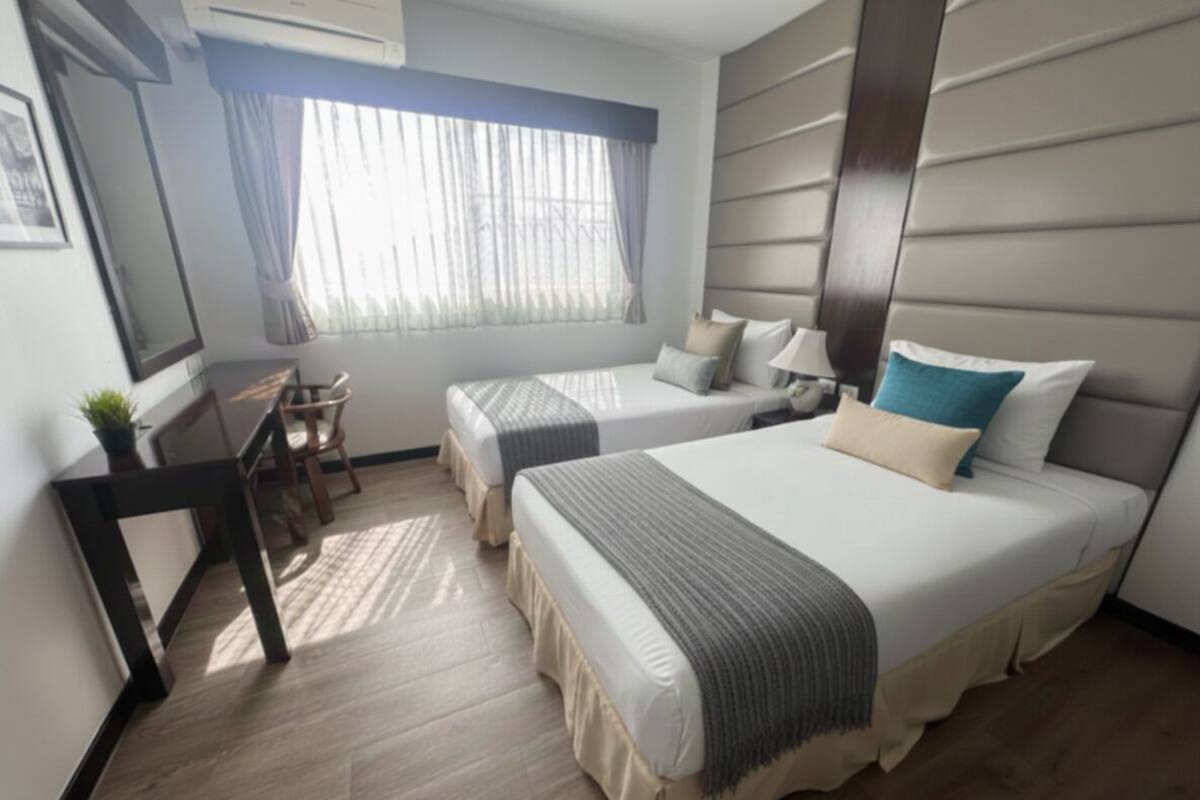 A hotel room with two beds, a desk, and a chair.