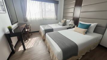 Habitación de hotel con dos camas, un escritorio y una silla.
