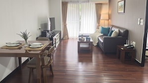 Una sala de estar moderna con comedor, un sofá, una mesa de centro y un televisor.