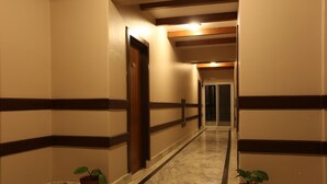 A hallway with marble flooring, wooden doors, and potted plants. - Pokhara Choice Inn (Pokhara)