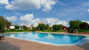 Piscina com céu azul claro e nuvens ao fundo.
