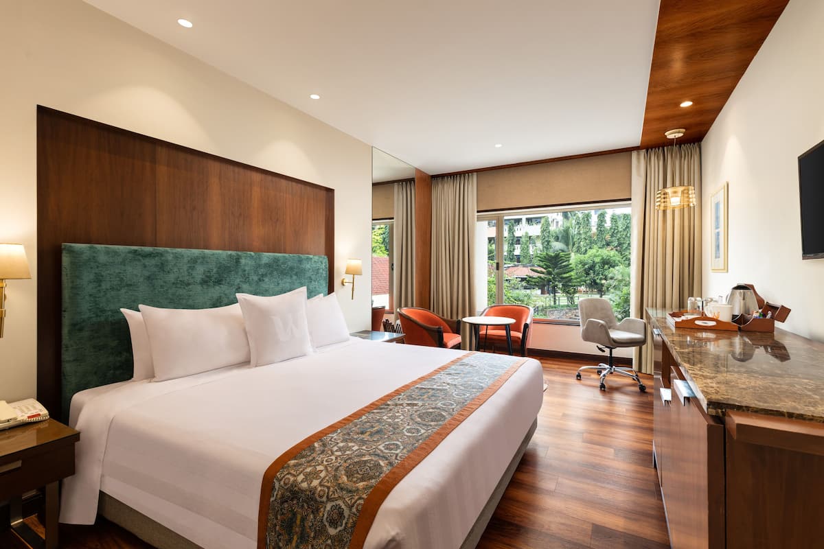 Habitación de hotel con una cama grande, un escritorio, una silla y vistas al exterior.
