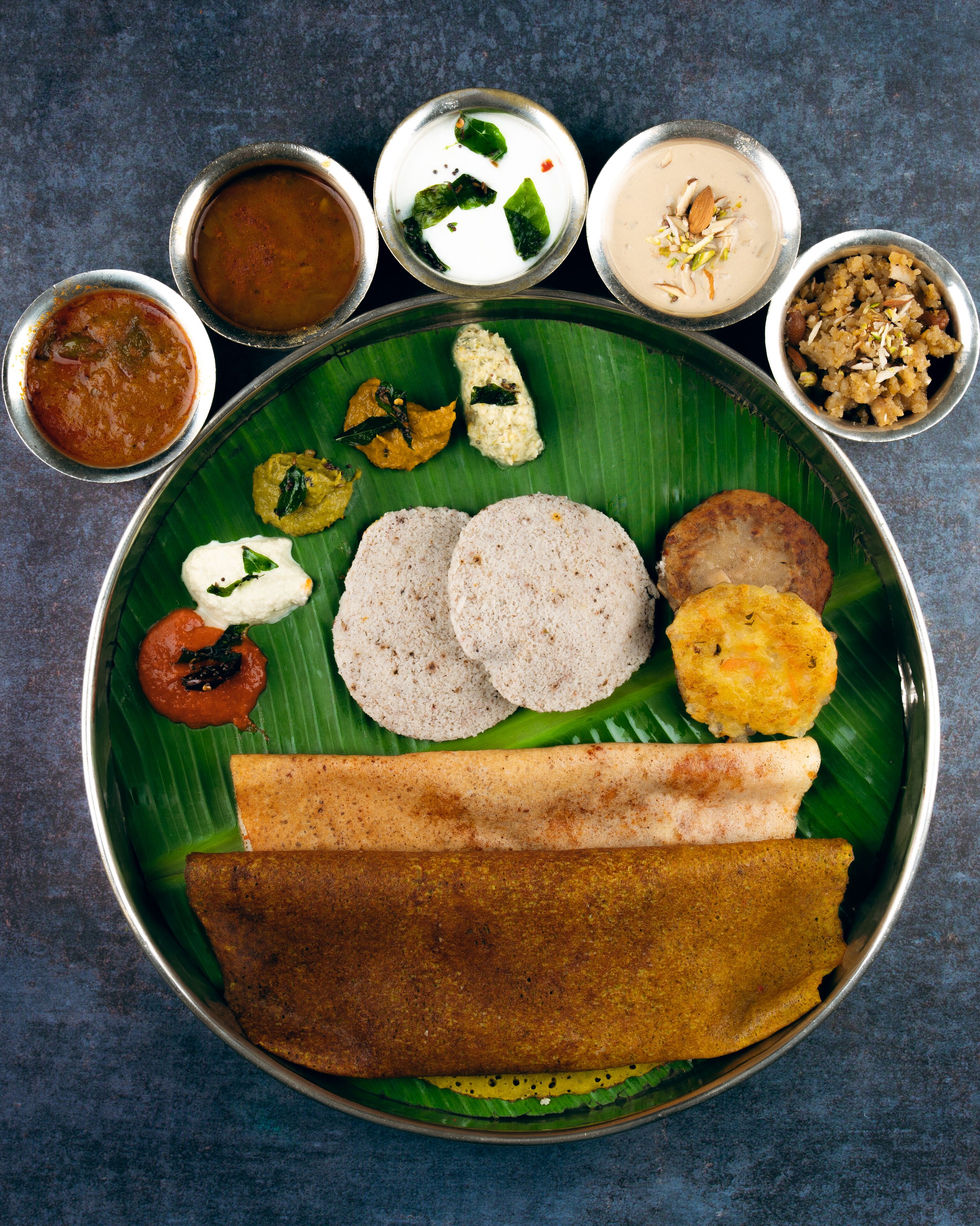 A plate with various Indian dishes including idli, dosa, and chutneys.