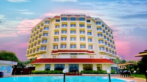 Um hotel com vários andares e uma piscina em primeiro plano.