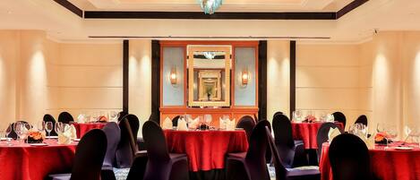 A banquet hall with multiple tables set for dining, each with chairs and table settings.