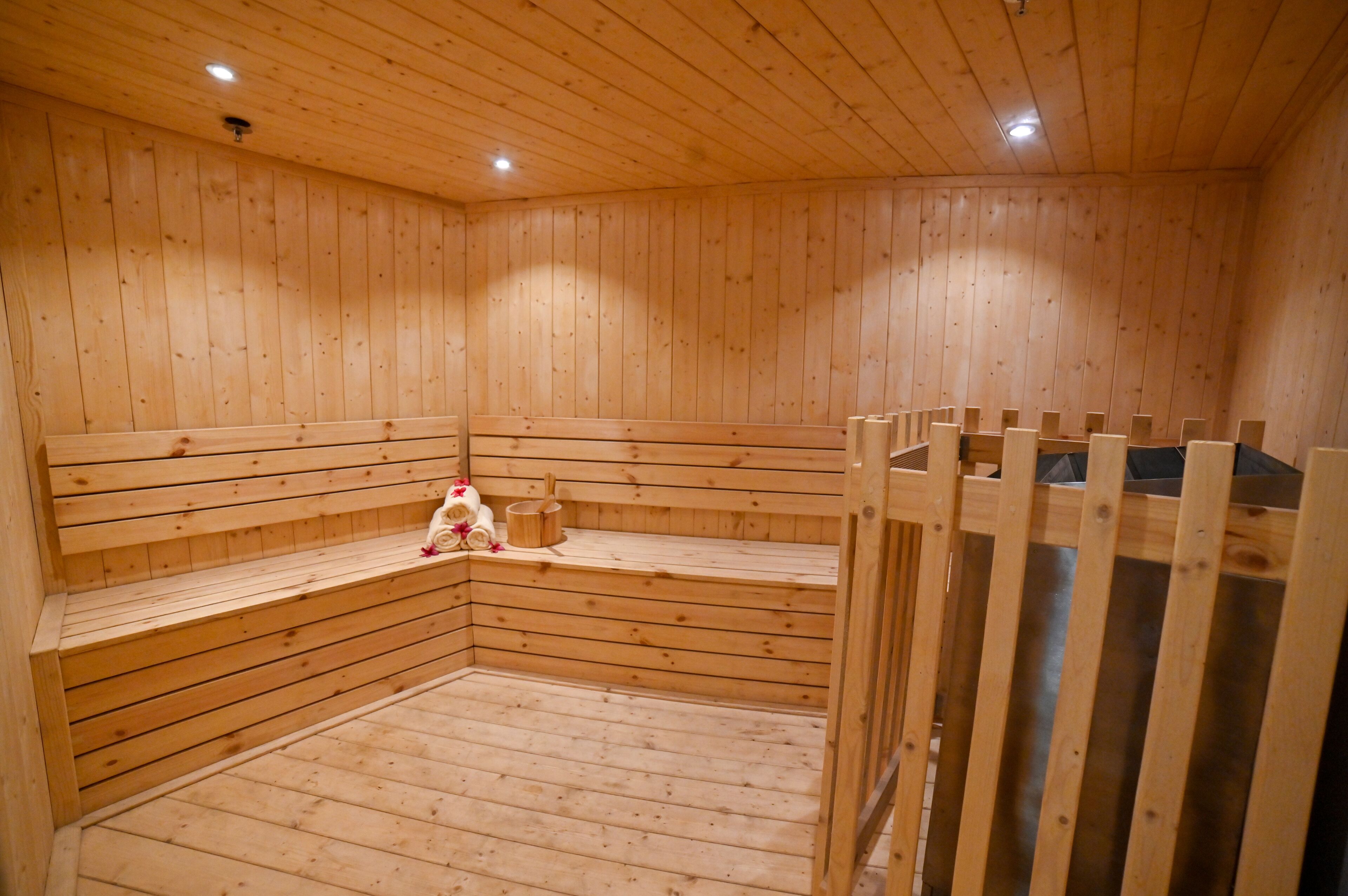 Una sauna de madera con bancos y un asiento de banco, un banco de madera y un asiento con banco.