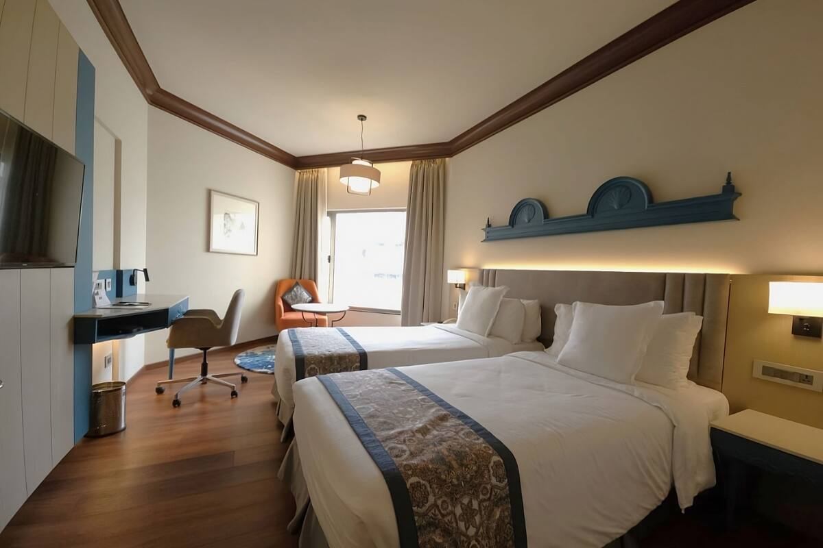 Una habitación de hotel con dos camas, un escritorio, una silla y una mesita.