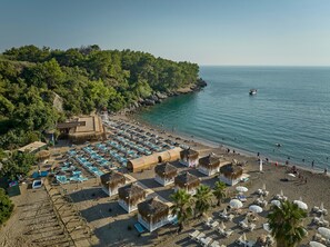 A beach resort with thatched-roof huts, sun loungers, and a pool area. - Litore Resort Hotel & Spa - All Inclusive (Alanya)