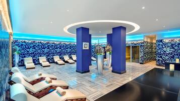 Un hall de hotel con un muro de patrón azul y blanco, una recepción y varios sillones dispuestos en semicírculo.
