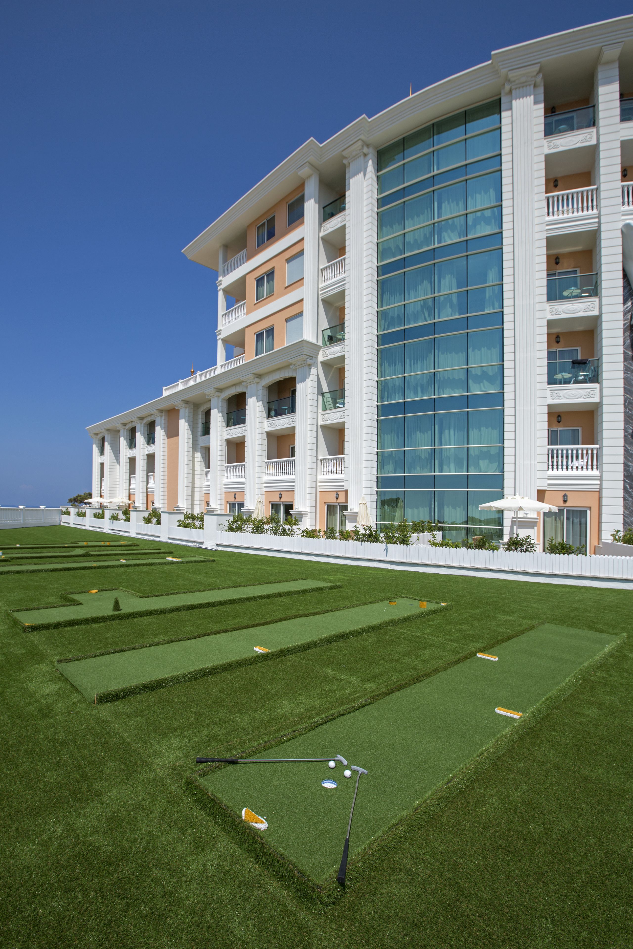 Un grande hotel con numerosi balconi, un prato curato e una vista libera sull'oceano.