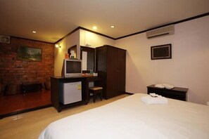 A hotel room with a bed, a desk with a computer, a chair, a small refrigerator, and a wardrobe. - Pathu Resort Ranong (Ranong)