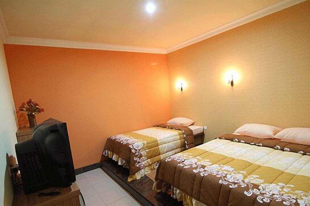 A hotel room with two beds, a desk, and a chair.