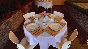 A round dining table set for four with white tablecloths and gold cutlery. - Patria Palace Hotel (Blitar)