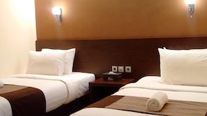 A hotel room with two beds, each with white linens and brown headboards. There are wall-mounted light fixtures on either side of the beds. - Patria Palace Hotel (Blitar)