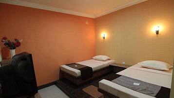 Habitación de hotel con dos camas individuales, un escritorio y una silla.