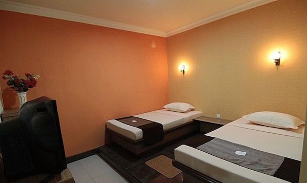 A hotel room with two single beds, a desk, and a chair. - Patria Palace Hotel (Blitar)